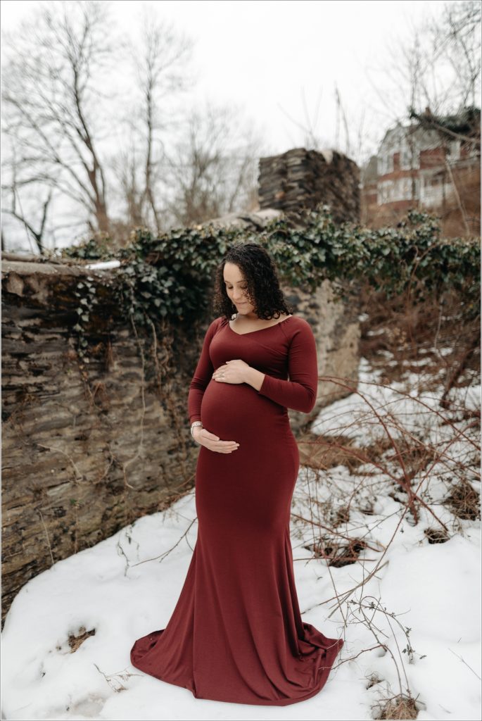 pregnant woman in long red maternity dress with maryland maternity photographer at ruins at st.johns in harpers ferry