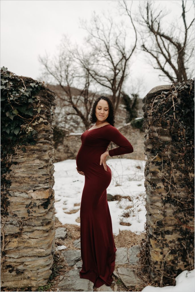 pregnant woman in long red maternity dress with maryland maternity photographer at ruins at st.johns in harpers ferry
