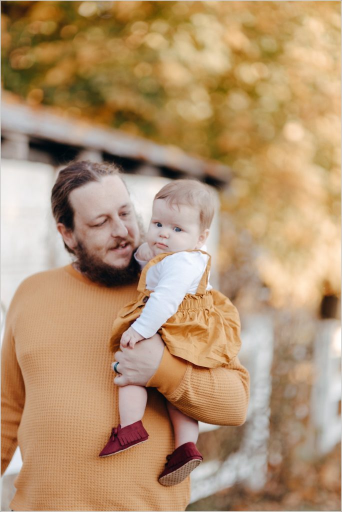 dad holds baby both wearing mustard fall outfits for swva photography