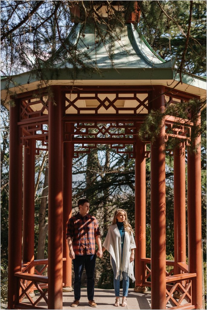 couple stands in sunlight at US national arboretum under red structure