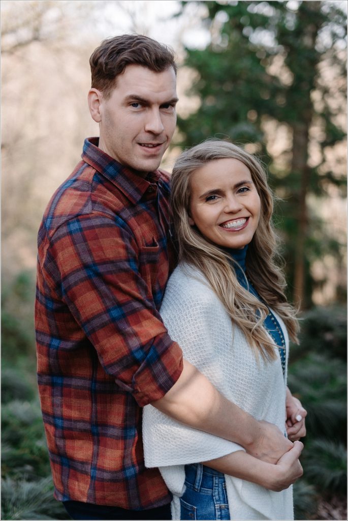 couple poses in asian garden for national arboretum engagement photos in red plaid and a white sweater