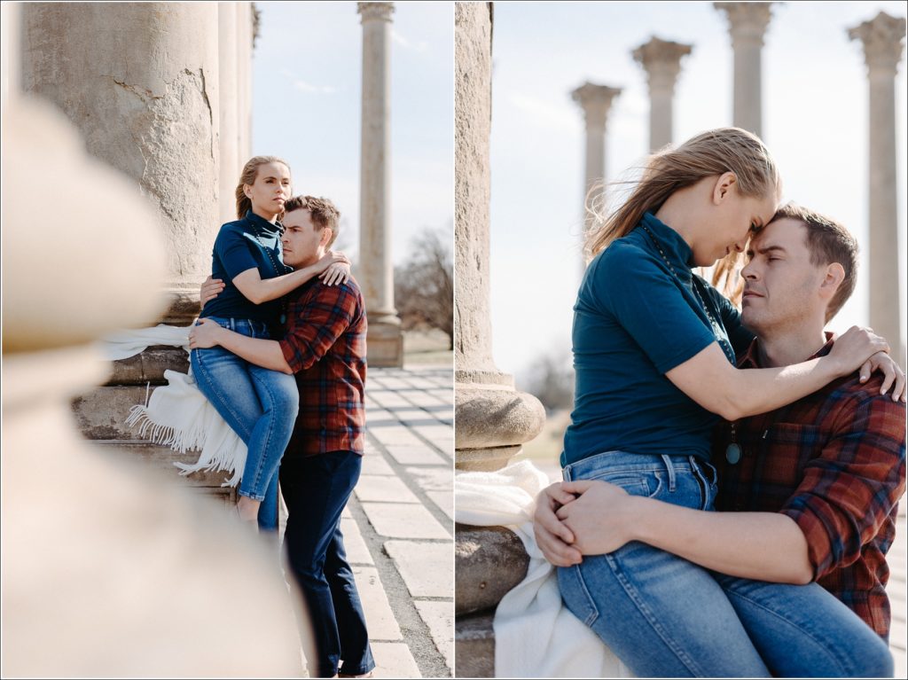 woman sits against columns posing with fiancé for national arboretum engagement photos wearing red plaid and teal turtleneck and jeans