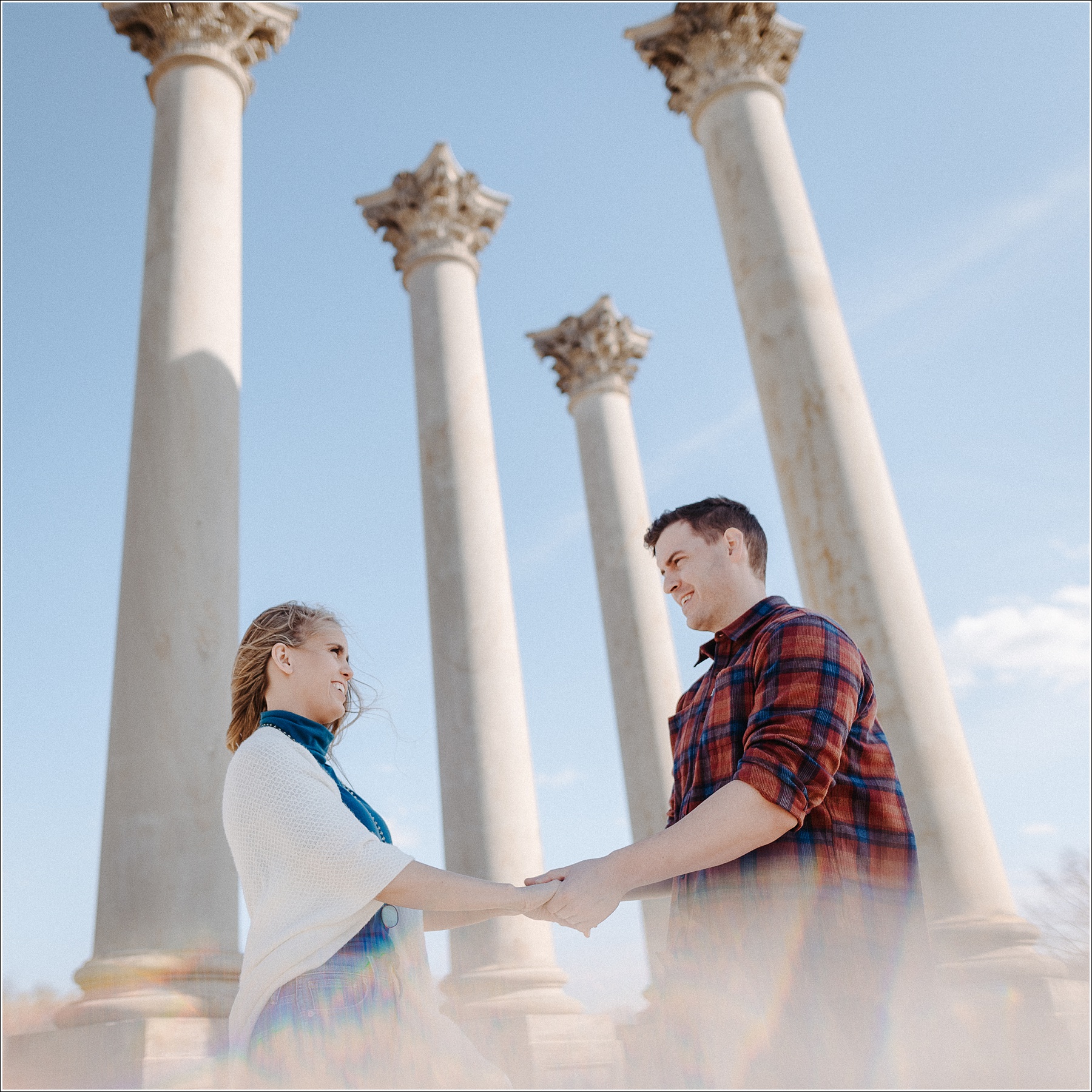 couple holds hands in front of the columns at the national arboretum