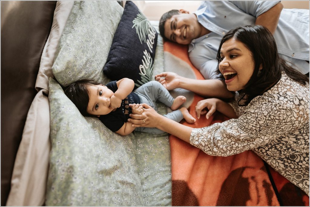 mom and dad lie on bed in newborn photography at home