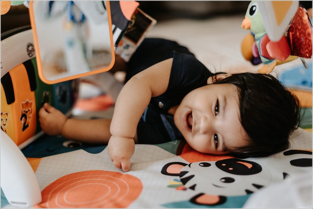 baby plays on colorful floormat in home session