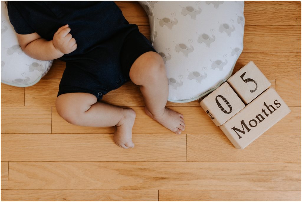 baby feet and blocks that say 5 months on wooden floor