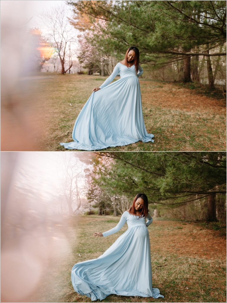 woman in blue maternity dress poses in front of green trees with rainbow prism