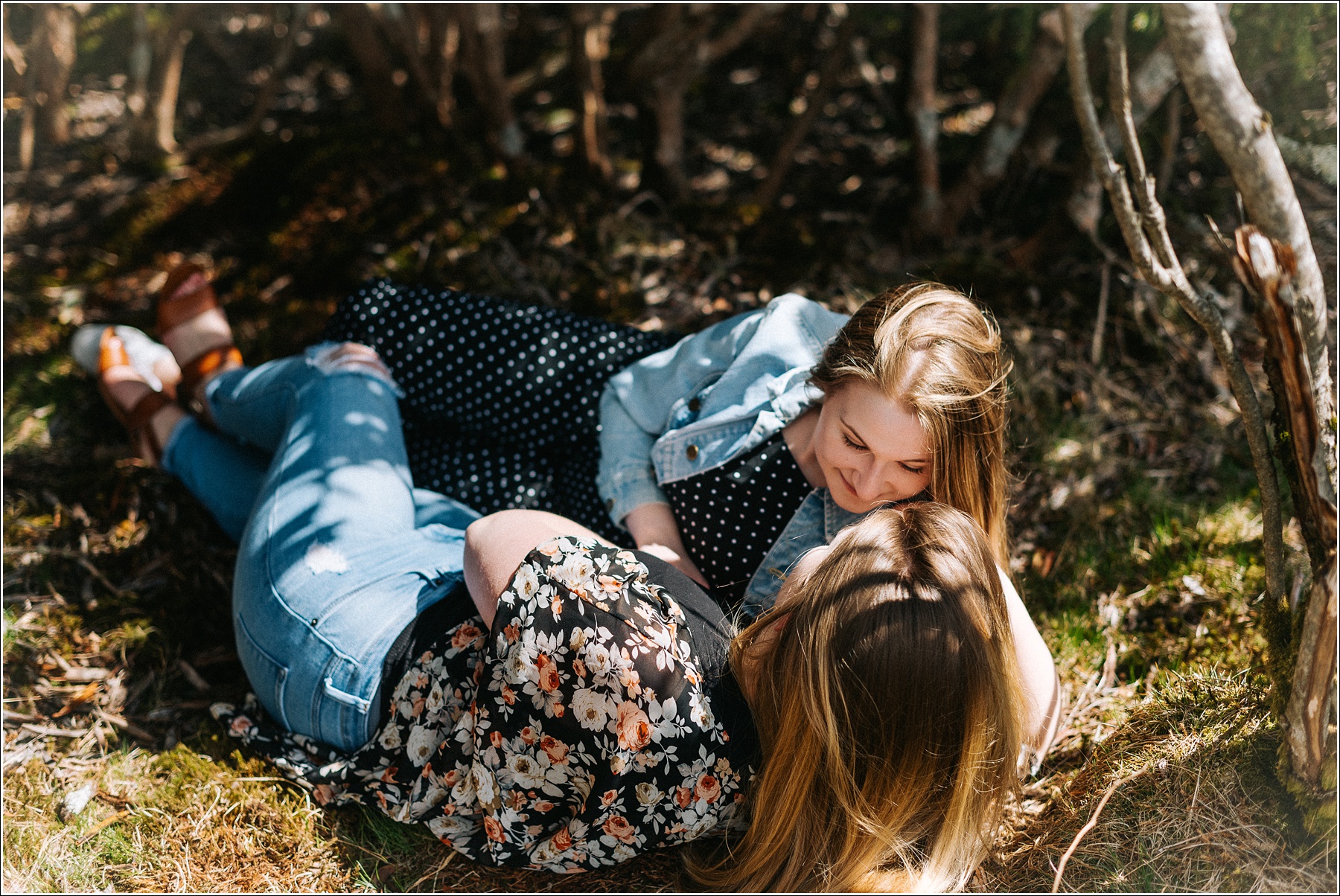 two women lay in the brush on roan mountain in jeans and floral and polka dot tops