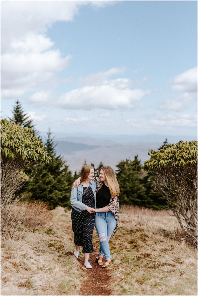two women in jeans and floral and polka dots walk together on carver's gap roan mountain