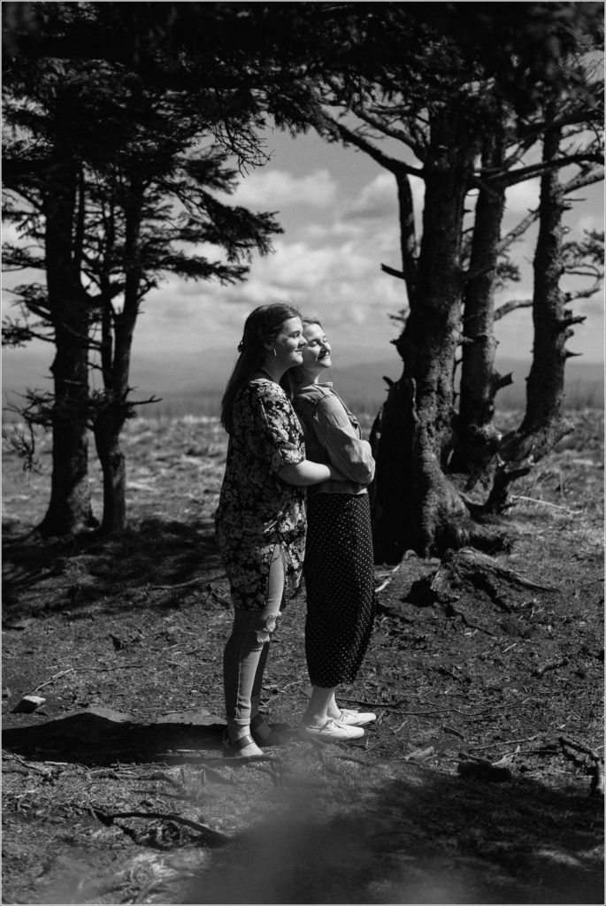 black and white photo of two women embracing with sunlight on their faces on roan mountain
