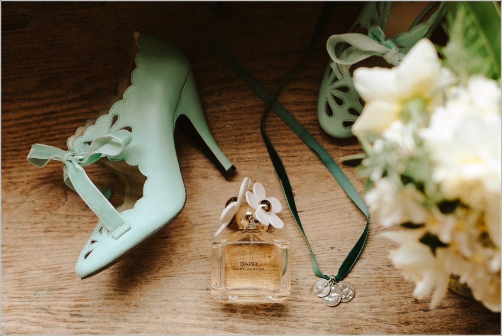 bridal details at the barns at chip ridge with shoes and perfume, a necklace, and flowers