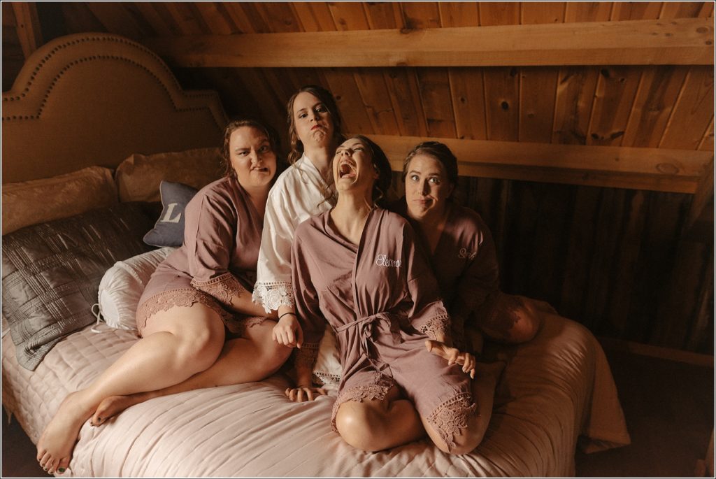 bridesmaids make goofy faces sitting on the bed at the barns at chip ridge