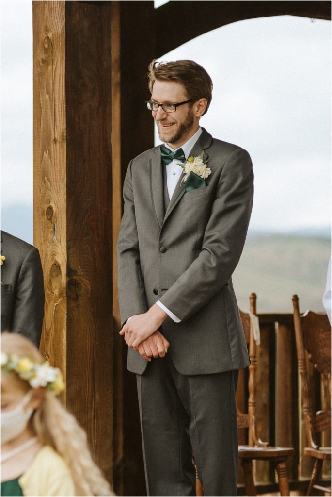 groom watches bride come down the aisle with a smile on his face at the barns at chip ridge
