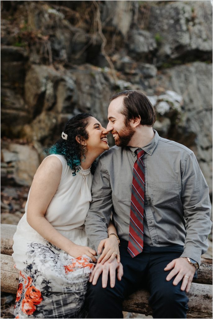 couple snuggles up at great falls virginia for photoshoot in white dress and grey button up shirt