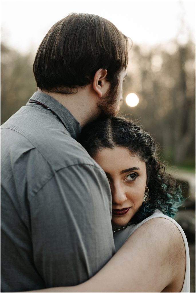 couple snuggles up in white dress and pearls and grey shirt at sunset for dc photoshoot