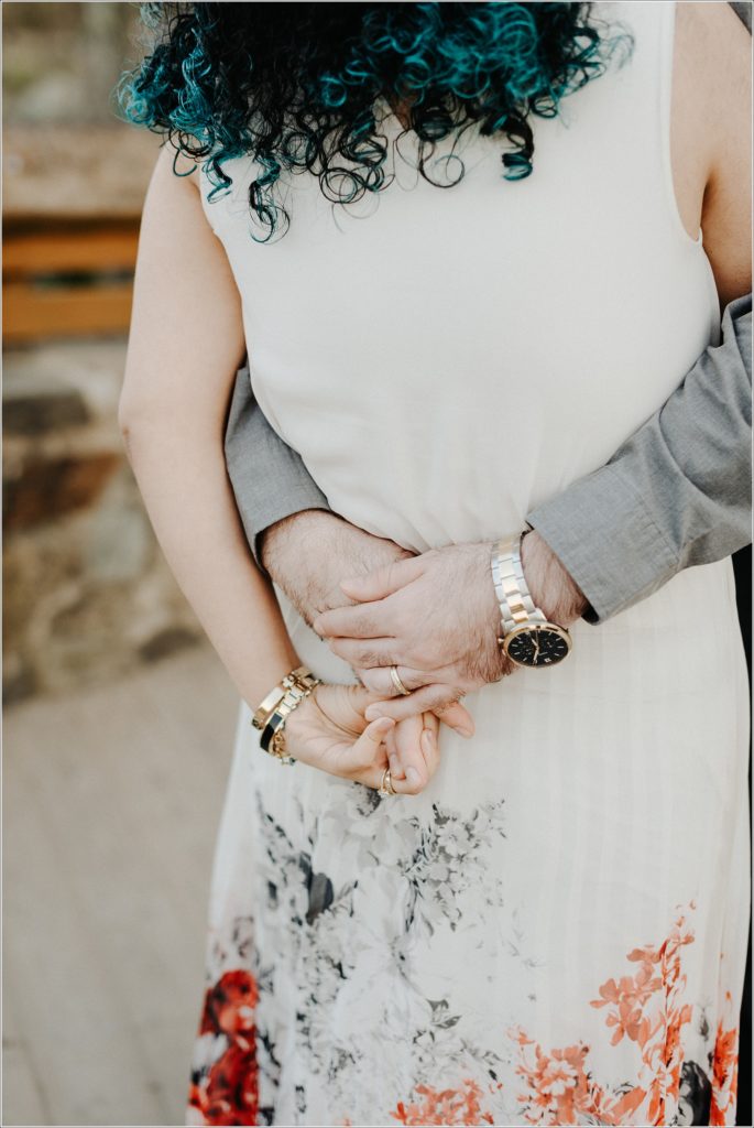 couple snuggles up at sunset with grey button and red tie and white dress with pearls at great falls state park for photoshoot