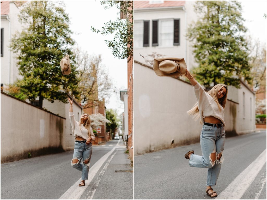 girl tosses cowgirl hat in street in sweater and jeans in downtown Frederick alleyway