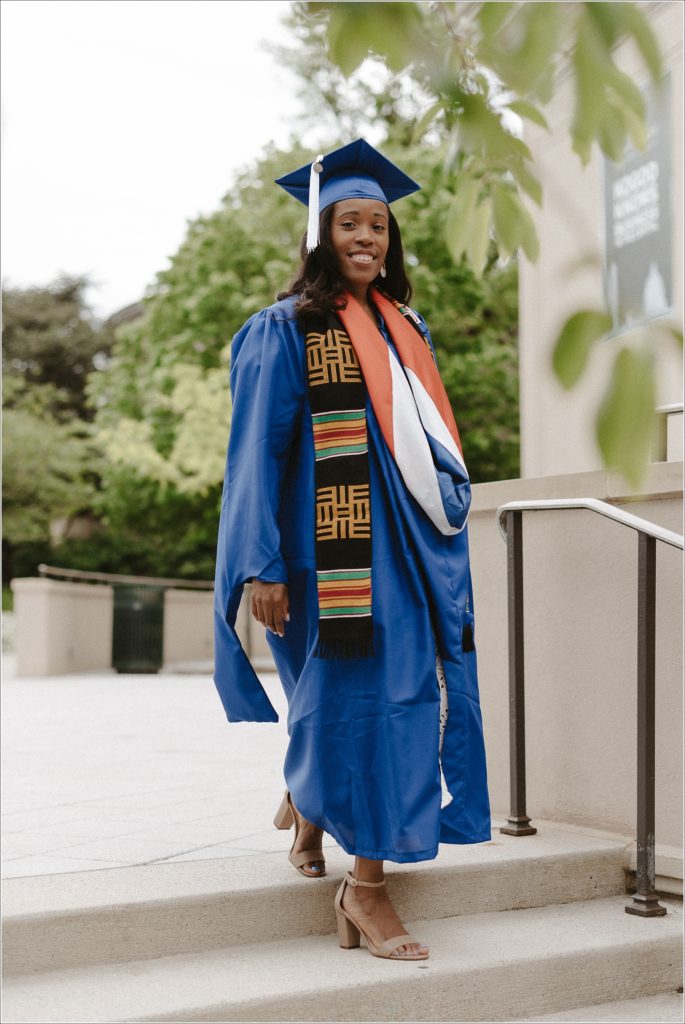 american university grad in blue cap and gown walks down stairs in graduation photos