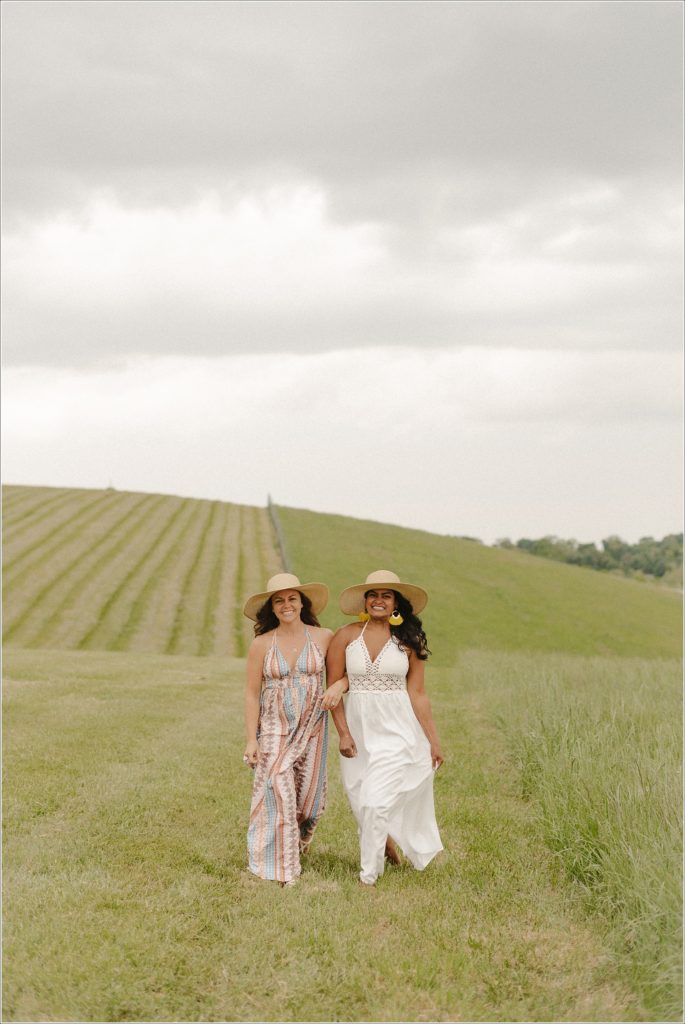 best friends run in sundresses in field at linganore winery with stormy sky