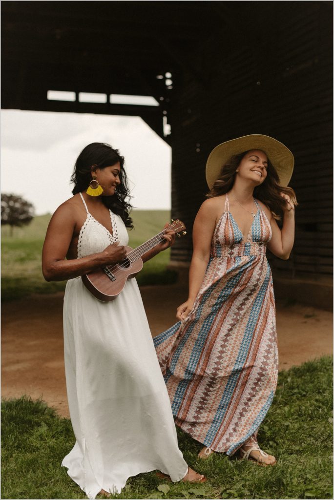women in sundresses play ukulele and dance underneath a barn