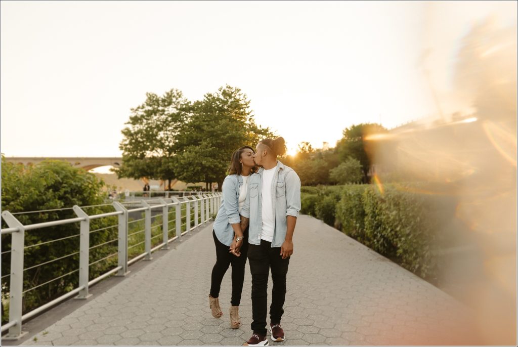 couple kisses by the water in engagement photos in georgetown wearing jean material