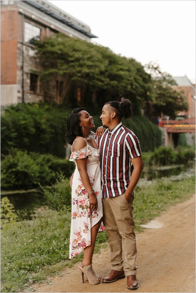 couple laughs together on c&O canal in georgetown engagement photos