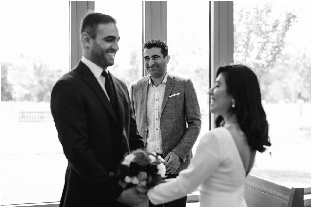black and white photo of man smiling behind bride and groom in courthouse wedding in maryland