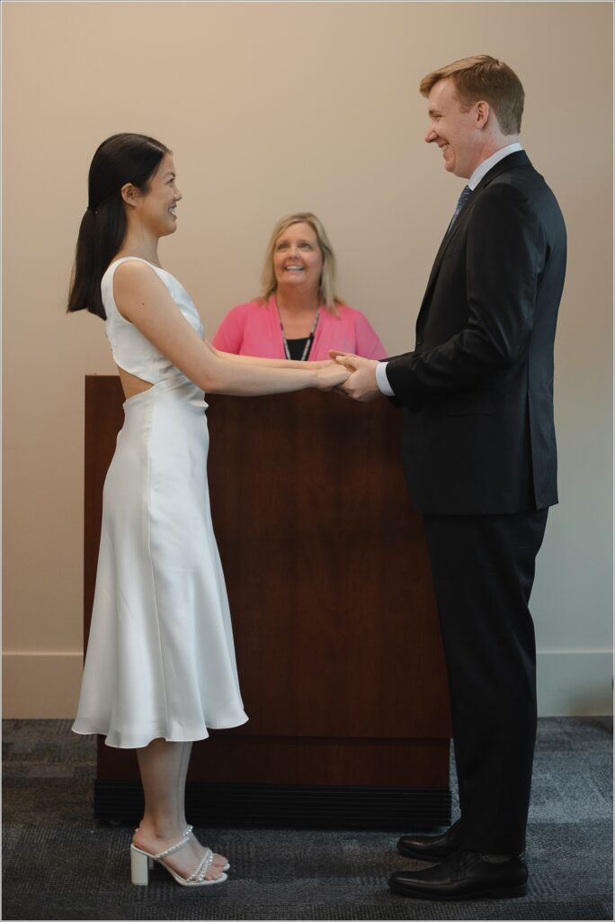 a woman in a white white dress and man in black suit stand at their howard county courthouse wedding