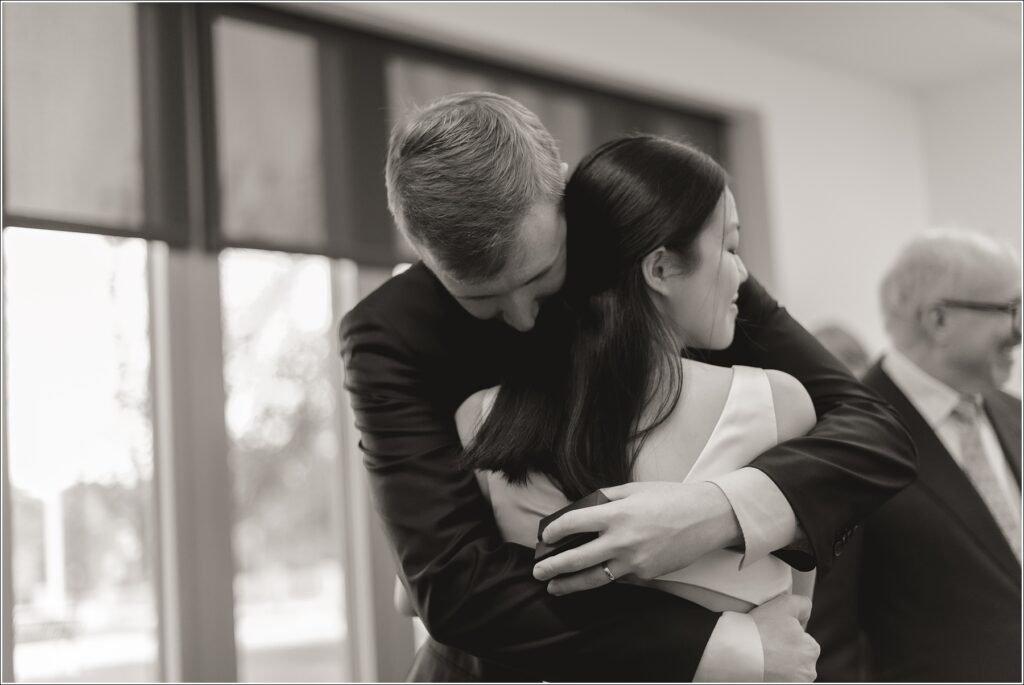 black and white photo of a man in a black suit and a woman in a silk wedding dress embracing at their howard county courthouse wedding