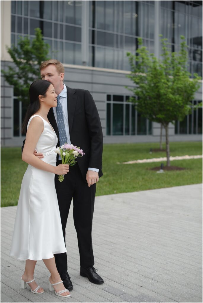 a woman in a white white dress and man in black suit stand at their howard county courthouse wedding