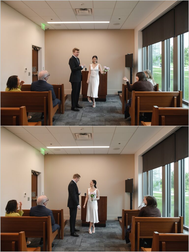 a woman in a white white dress and man in black suit stand at their howard county courthouse wedding surrounded by benches with family